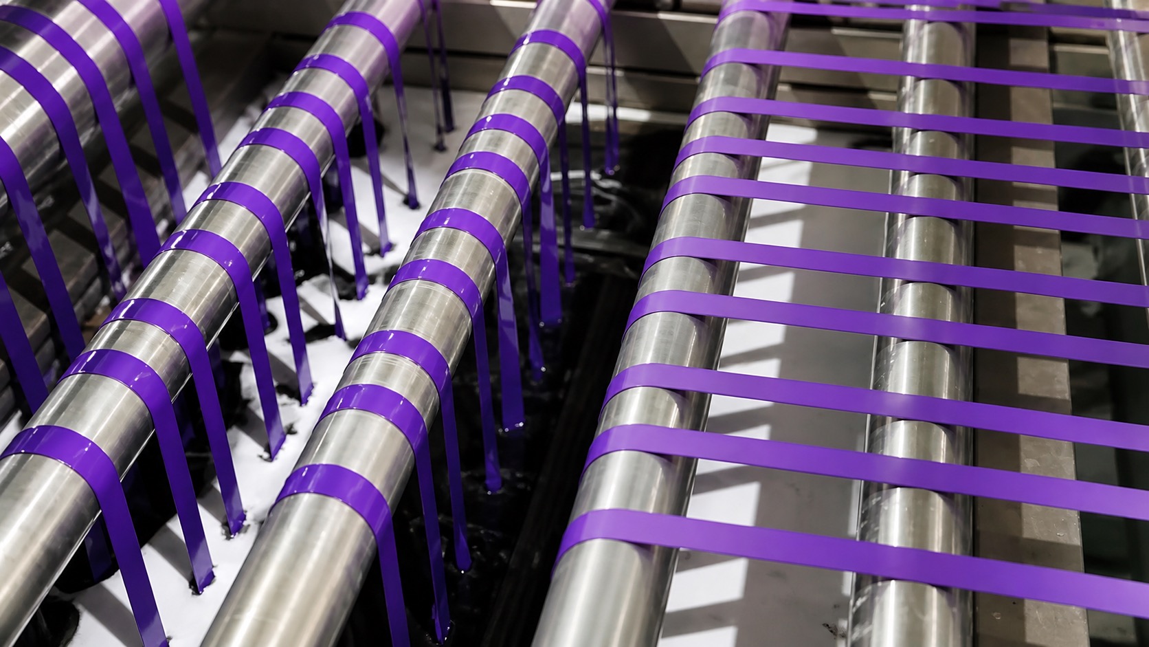 Ribbon dyeing close-up purple ribbon running through steel dye rollers, color-setting process